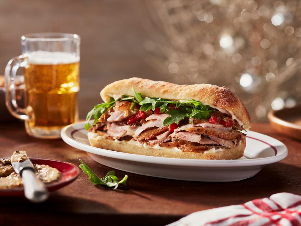 A Rome street food classic, the porchetta sandwich features herb-infused, slow-roasted pork belly slices in a crusty roll, offering a delicious blend of crispy skin and flavorful meat.
